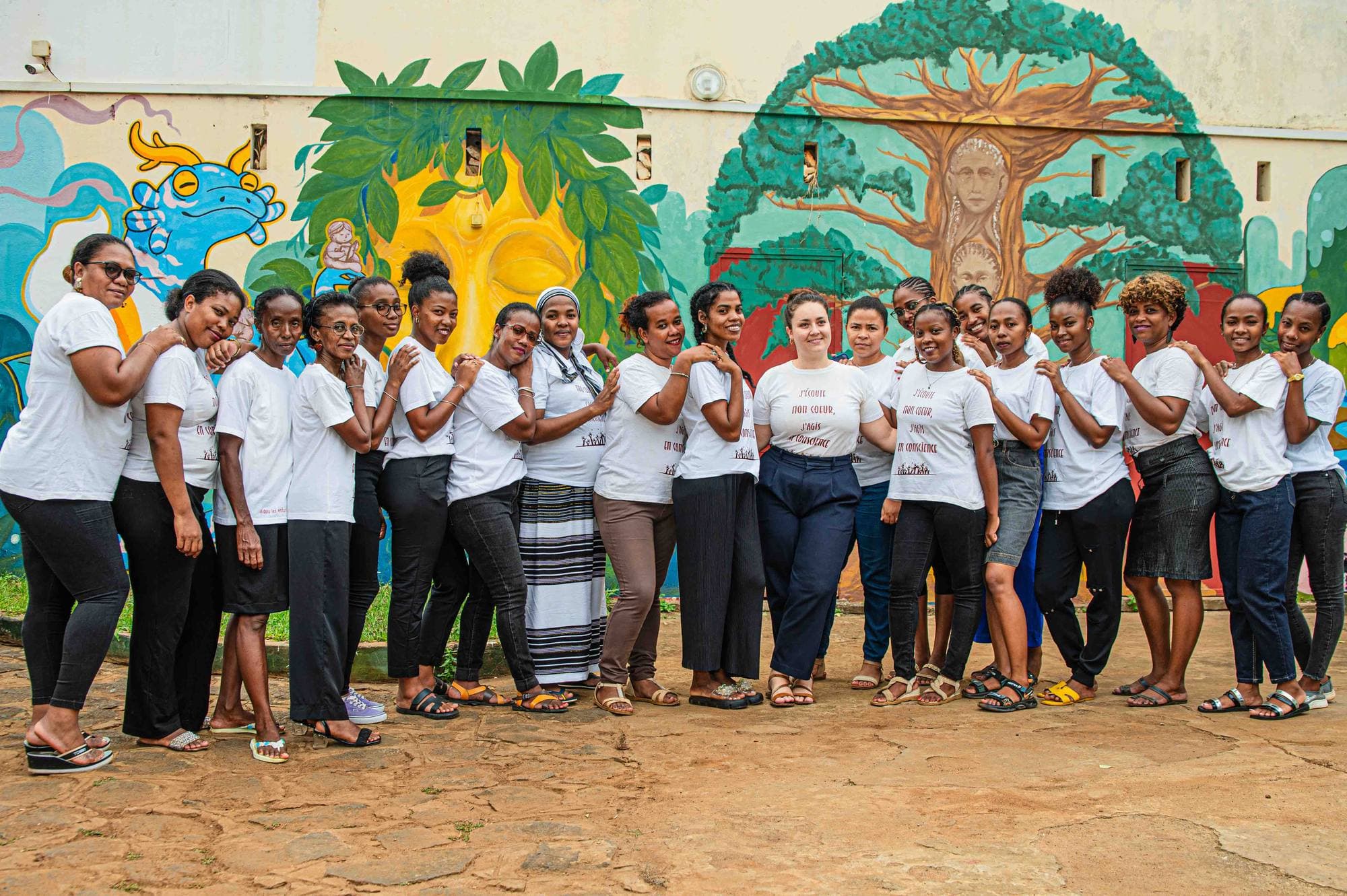 Un grand groupe de femmes de l’association devant une fresque colorée