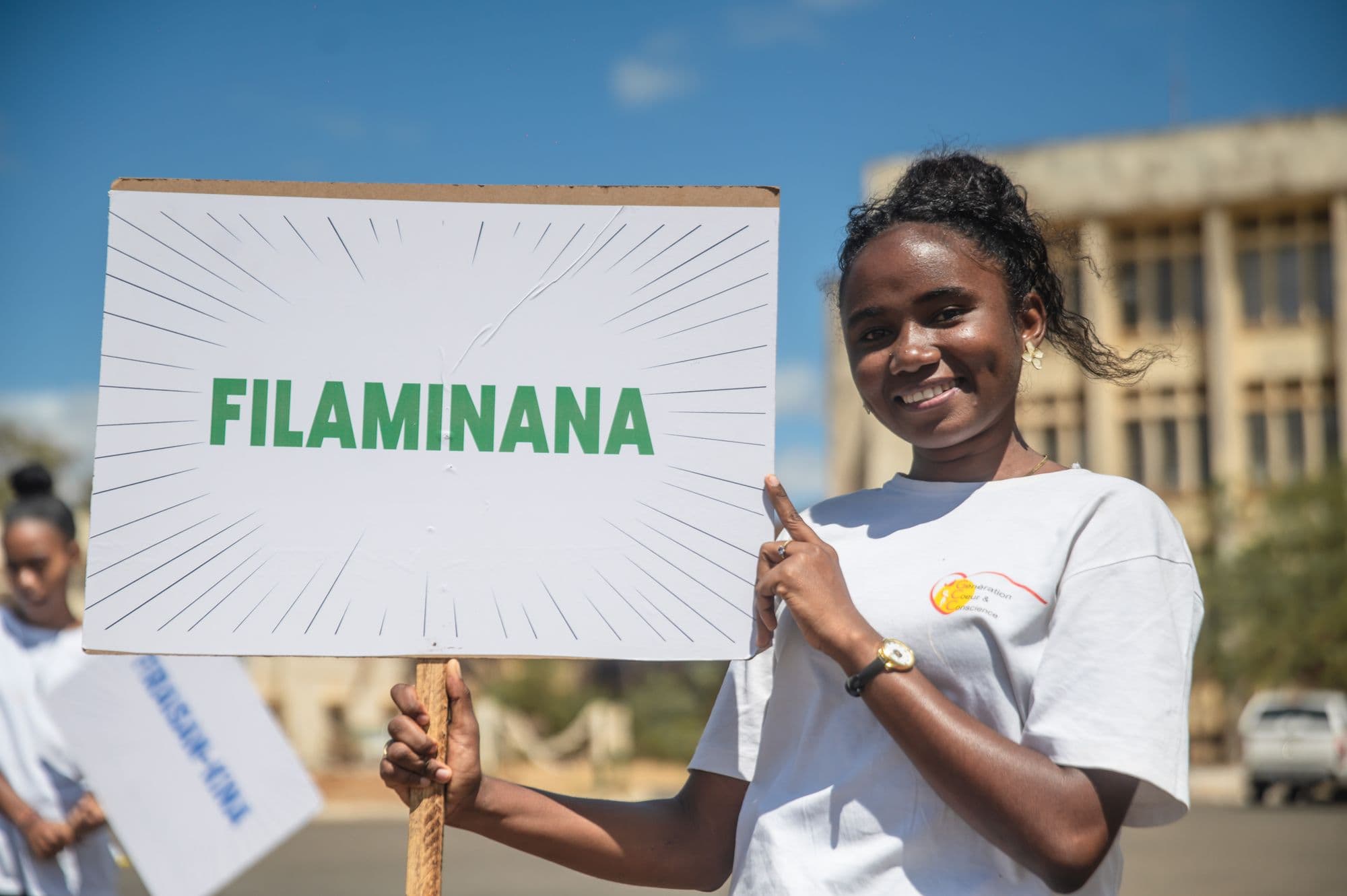 Une jeune femme tient une pancarte « Filaminana »