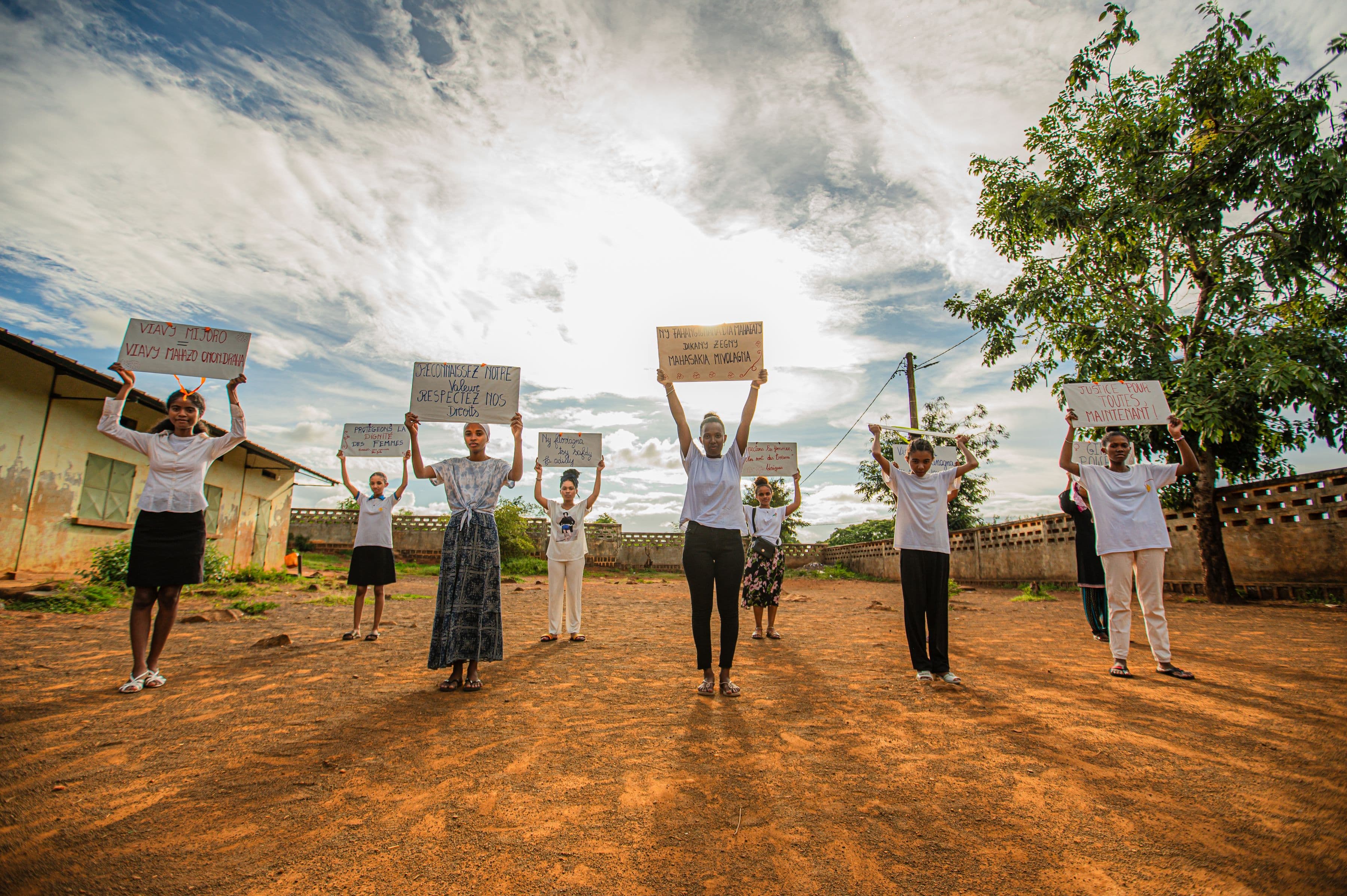 Des jeunes femmes brandissent des pancartes sous un grand ciel