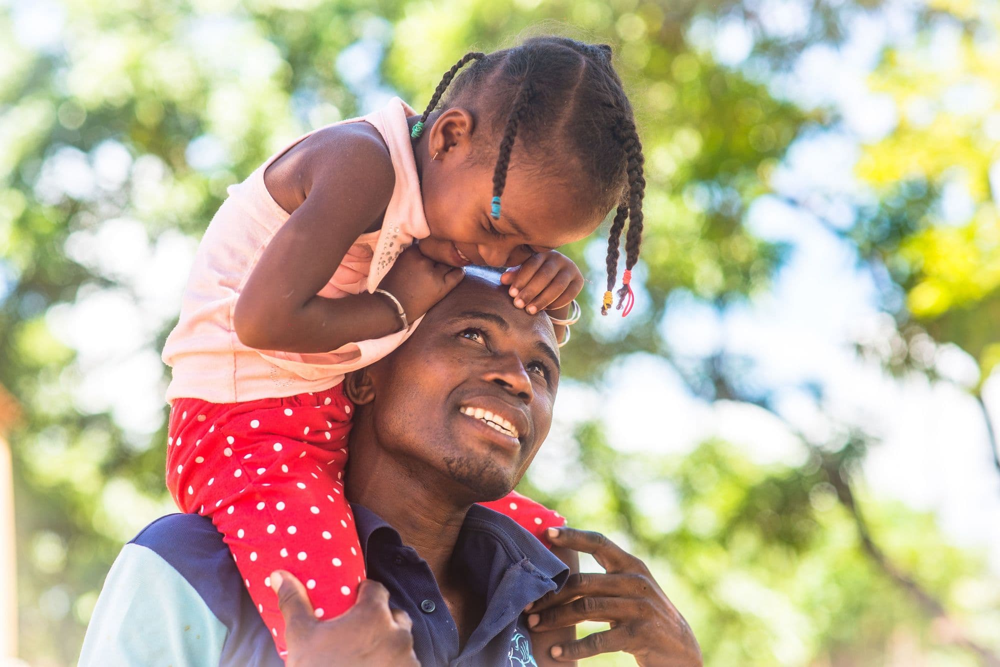 Un père porte sa fille sur ses épaules, tous deux souriants